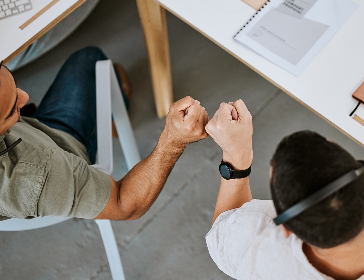 2 people fist bumping eachother in an office setting