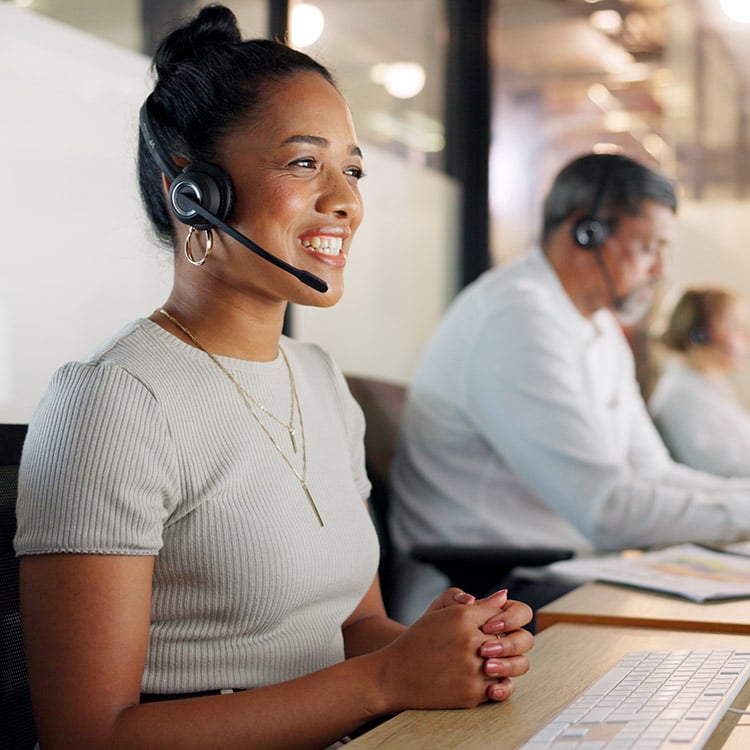 smiling Customer Support person at a computer with aheadset on