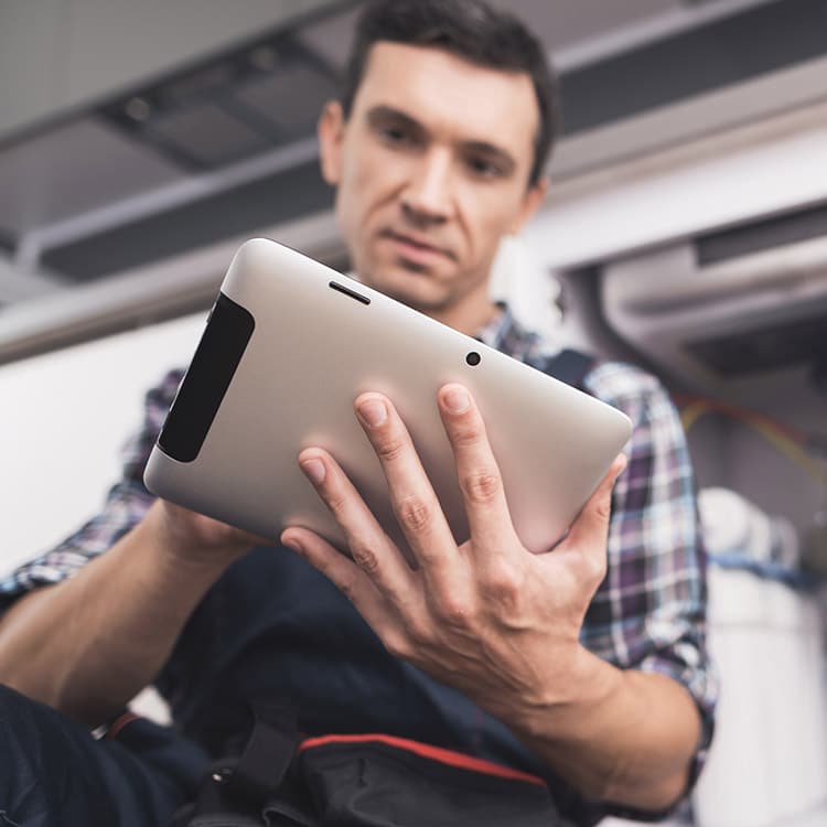 A technician in a home looking at something on a computer tablet