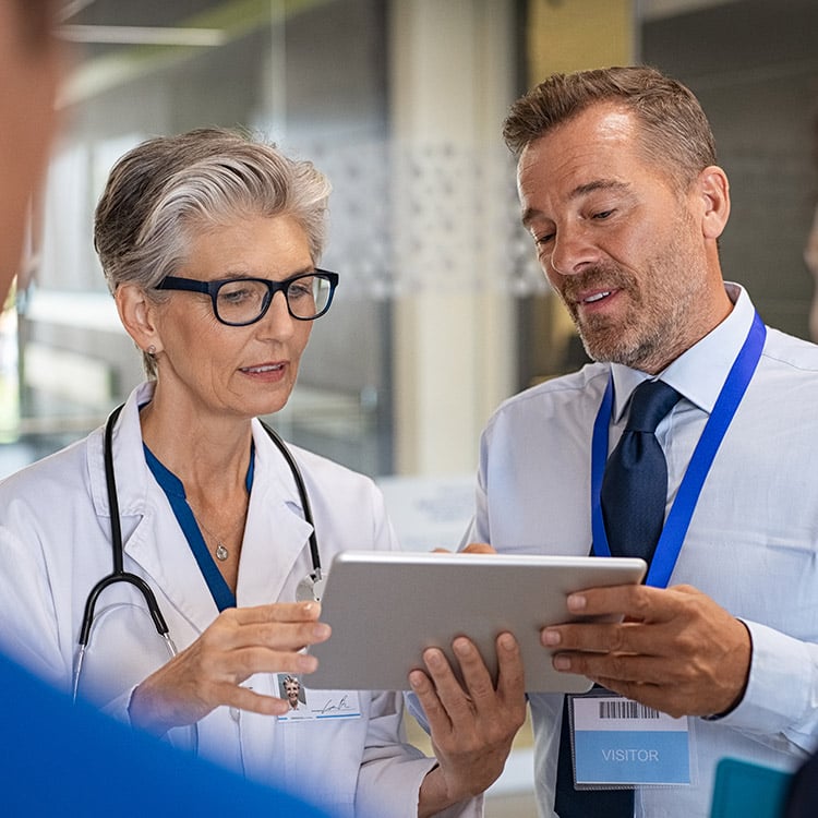 Two people having a discussion related to information on a computer tablet